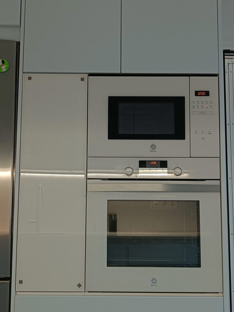 Cocina gris nube y blanco brillo con electrodomésticos y vitrina
