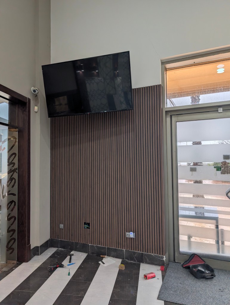 Barra y pared forradas en madera con estanterías a medida en un local